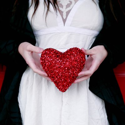 Woman holding a red heart over her stomach.